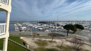 Ein Yachthafen mit zahlreichen vertäuten Booten, einem klaren Himmel und Blick aufs Meer.