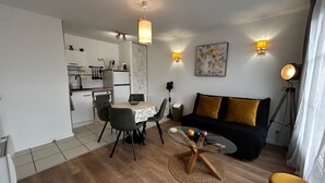 A compact living space with a dining area, a sofa, and a small round table. - Renovated T2 with WiFi and parking 200m from the Spa (La Roche-Posay)