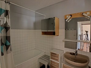 Bathroom features a shower, sink, and mirror, with a cabinet for storage.