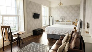 A bedroom with a large bed, a desk, a chair, a dresser, and a window with a view. - Beach Views, Elegant & Modernised 5BD Period Home (Tramore)