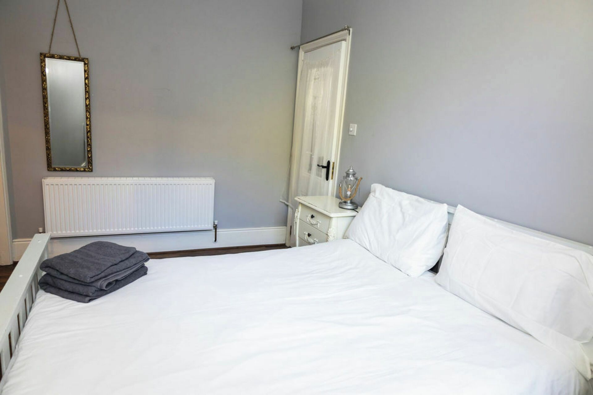 A bedroom with a bed, a dresser, a mirror, and a radiator.