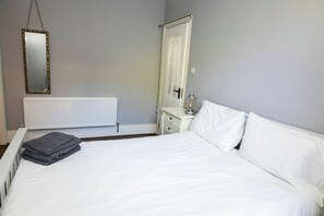 A bedroom with a bed, a dresser, a mirror, and a radiator. - Beach Views, Elegant & Modernised 5BD Period Home (Tramore)