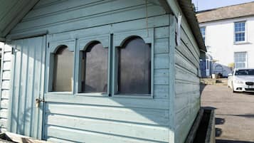 A light blue wooden building with three arched windows and a door.