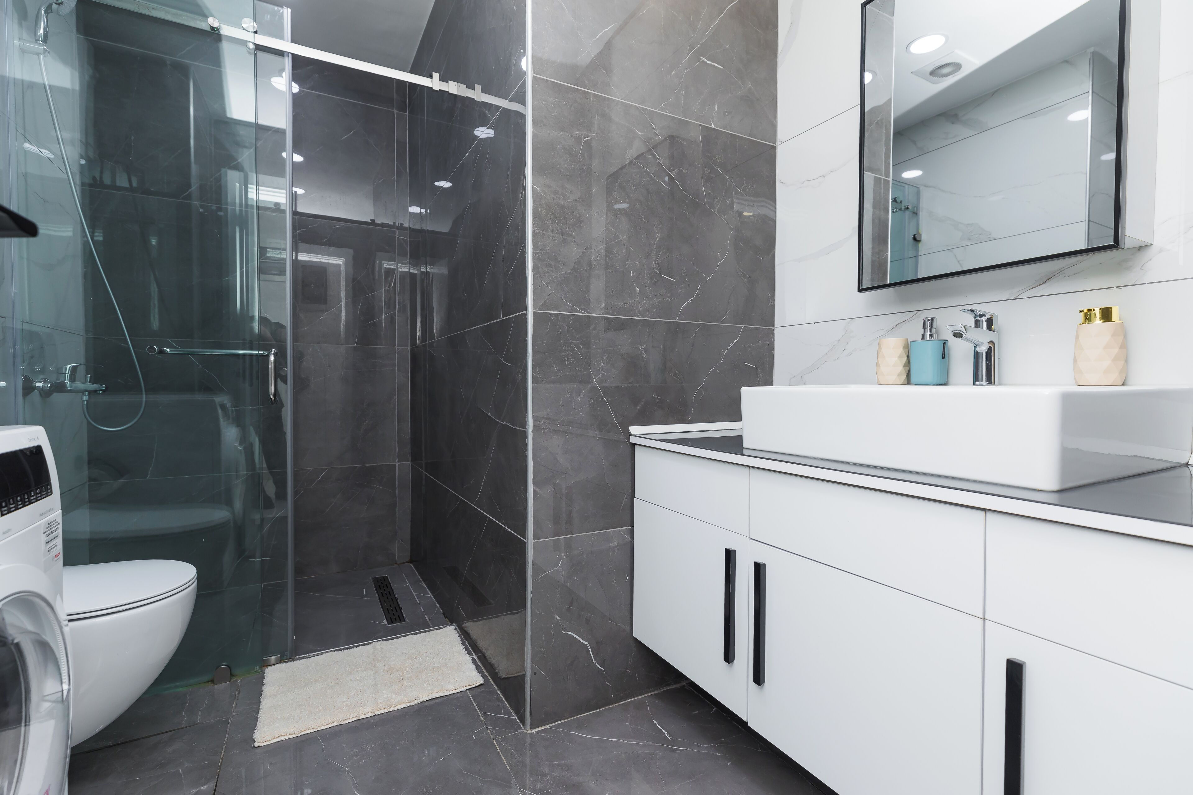 Une salle de bain moderne avec une douche à parois de verre, un lavabo blanc et un grand miroir.