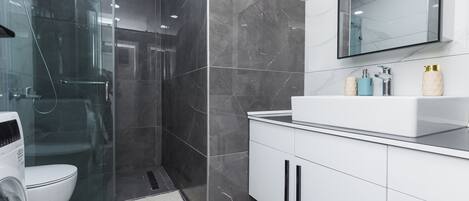 Une salle de bain moderne avec une douche à parois de verre, un lavabo blanc et un grand miroir.