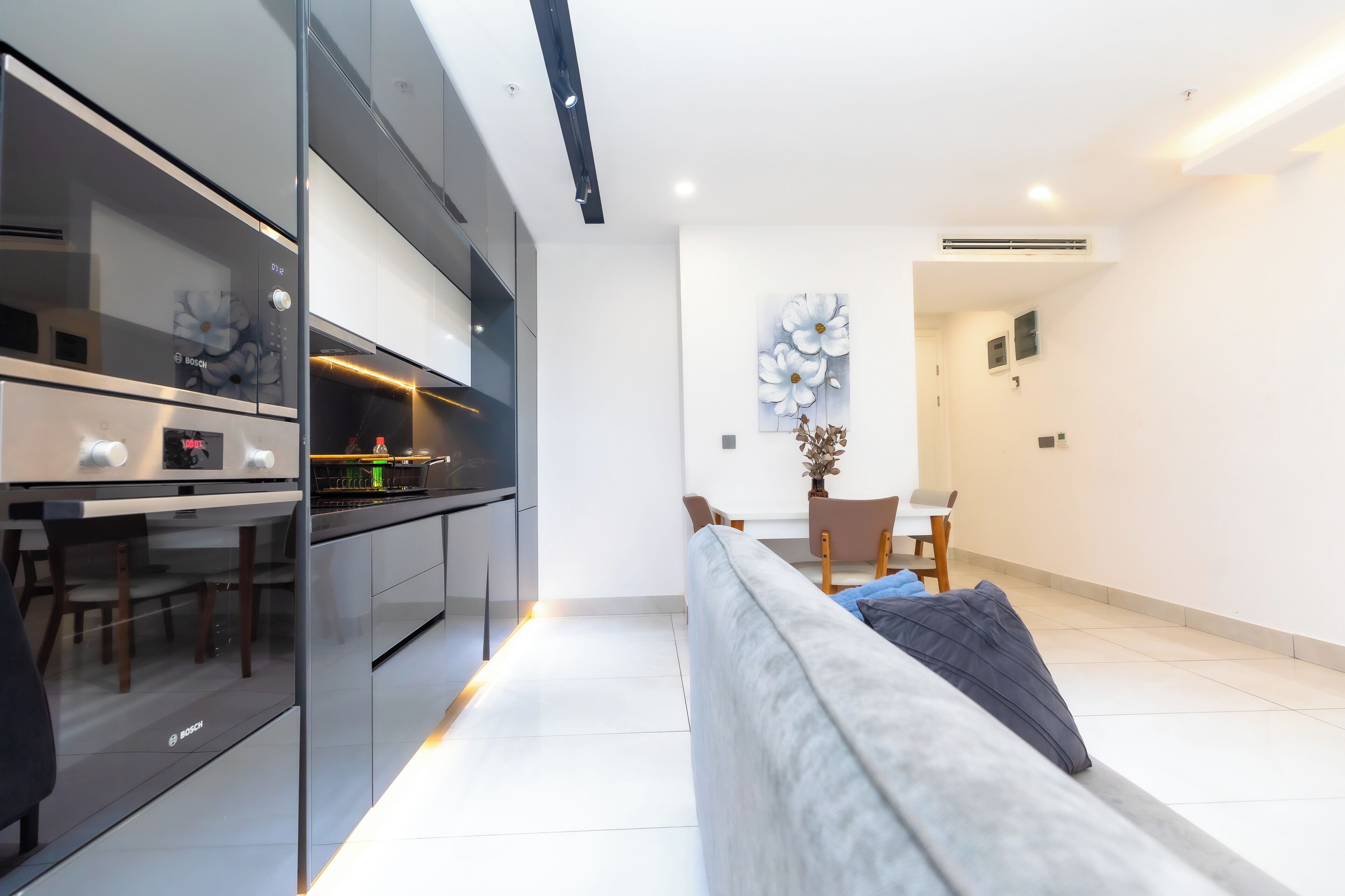 Una cocina moderna con electrodomésticos Bosch, un comedor con mesa y sillas, y una sala de estar con sofá.