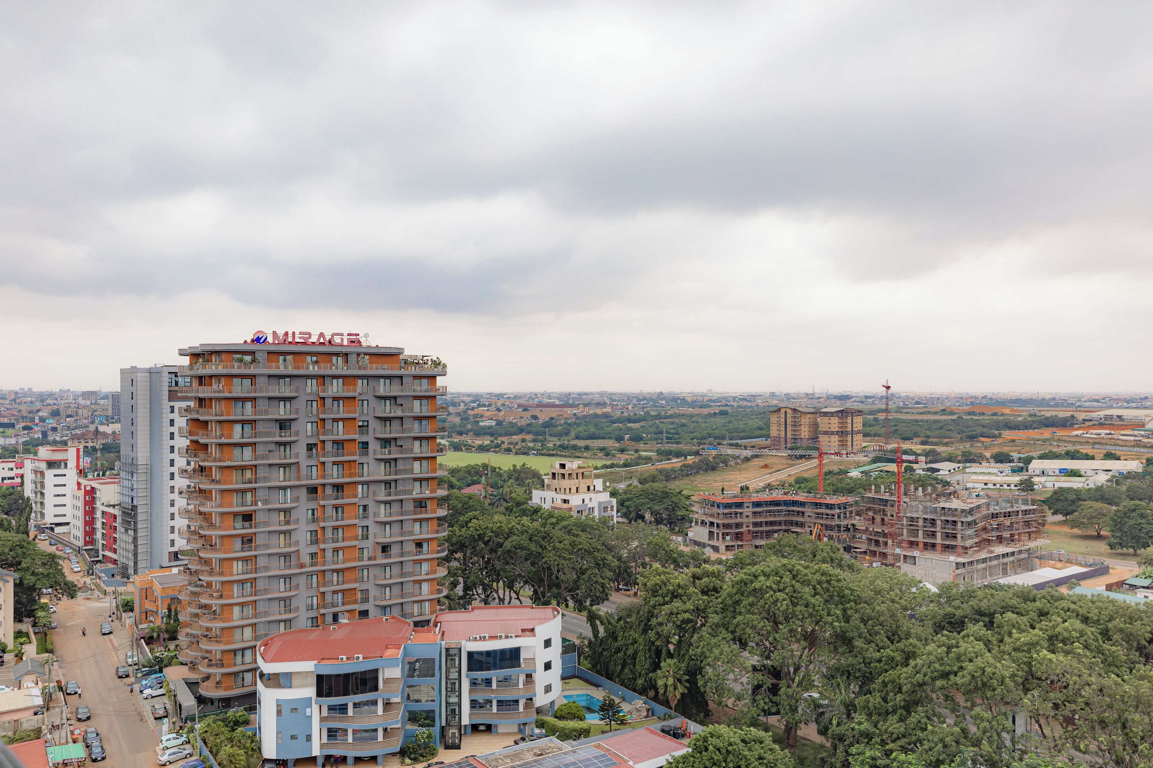 A high-rise building with multiple floors, surrounded by other buildings and greenery.