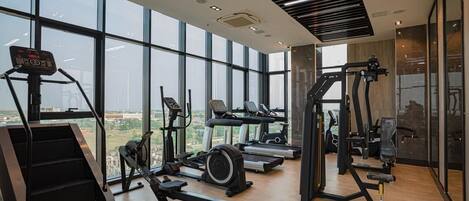 Una palestra moderna con diverse attrezzature per esercizi, ampie finestre e vista sulla città.