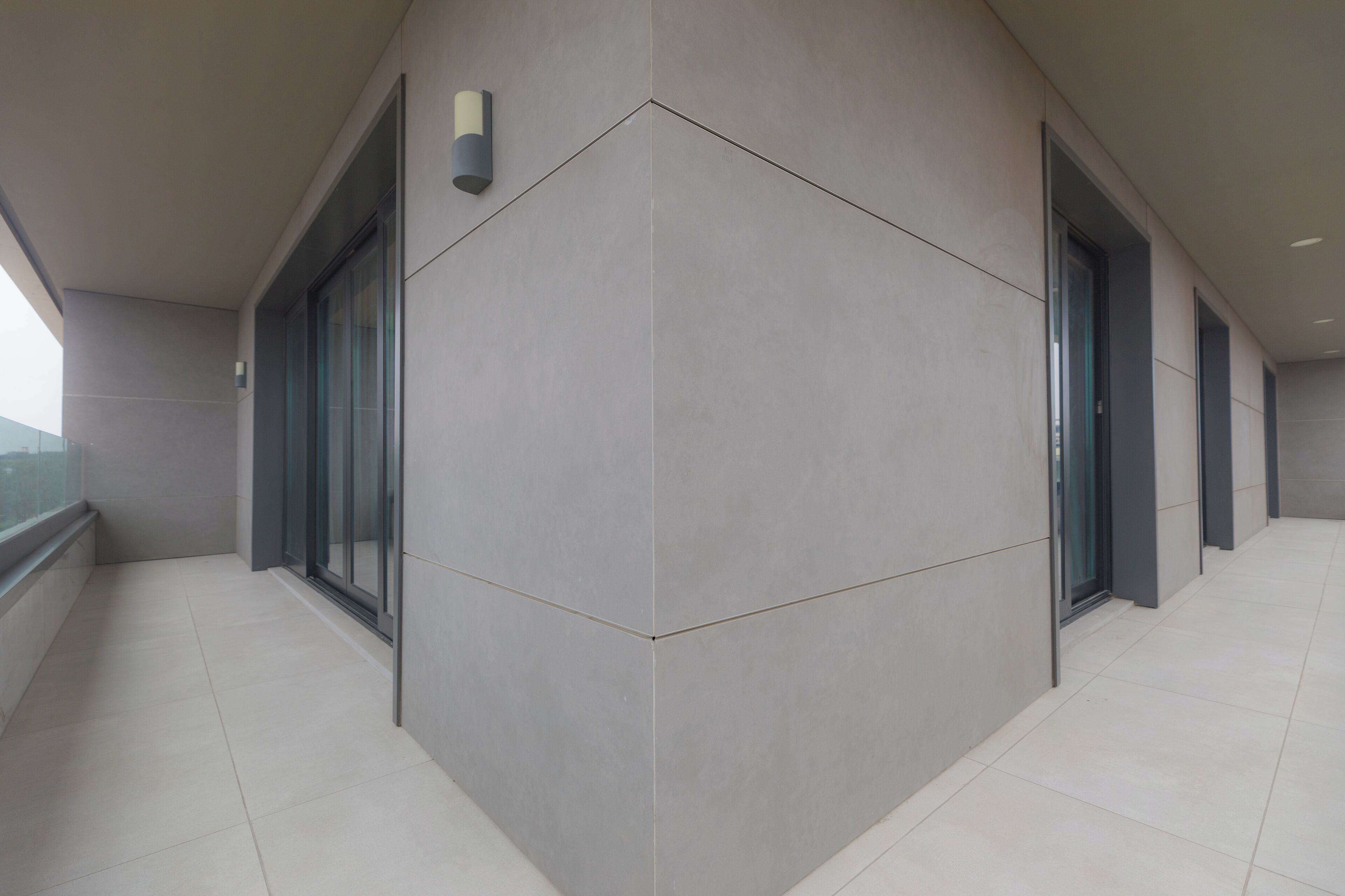 A modern building exterior with a clean, geometric design, large windows, and a tiled floor.