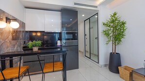 A modern kitchen with white cabinets, a black countertop, and a built-in stove. There are two wooden chairs and a potted plant. - Kass Towers (Accra)