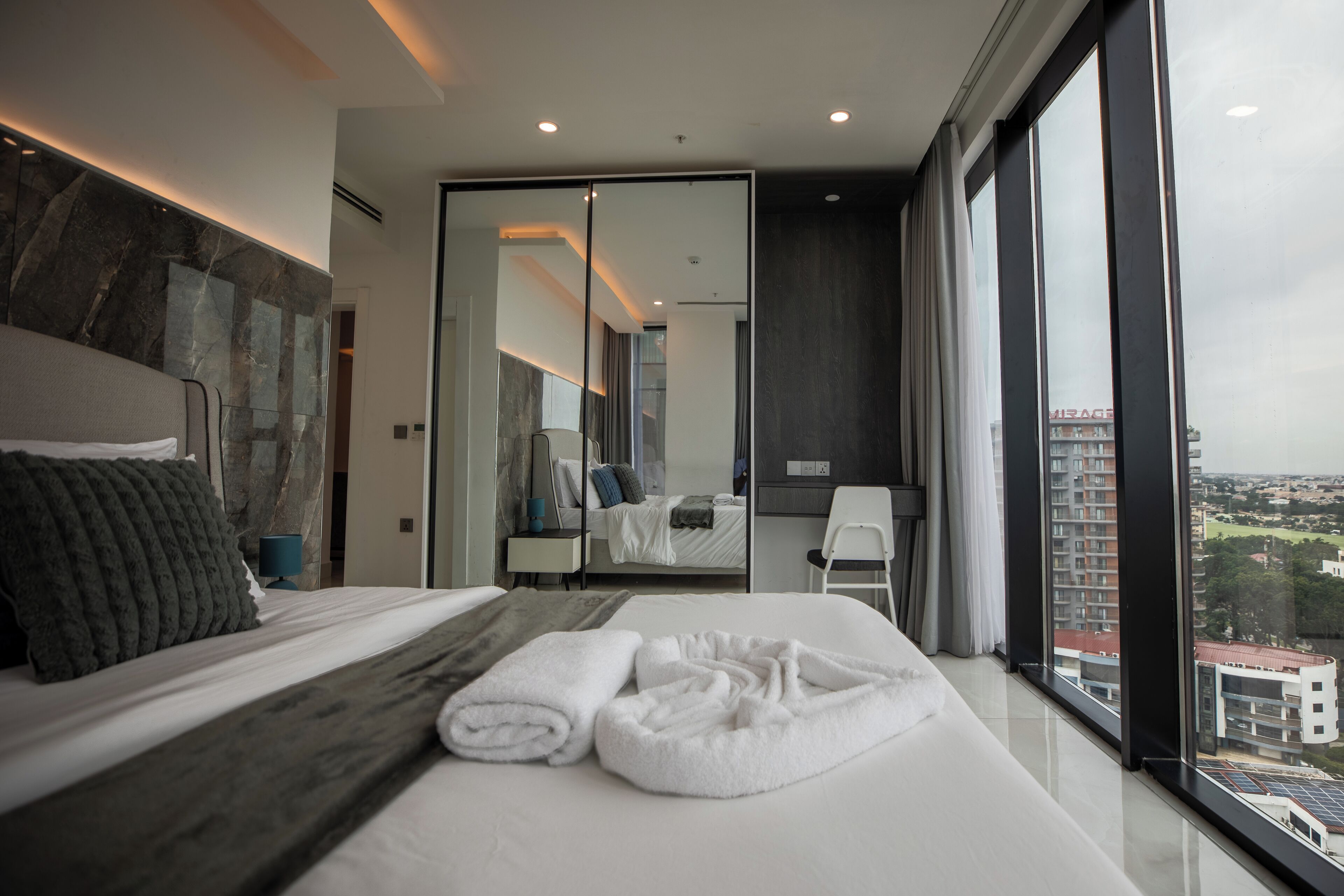 Una habitación de hotel moderna con una cama grande, vistas a la ciudad y una zona de trabajo separada.