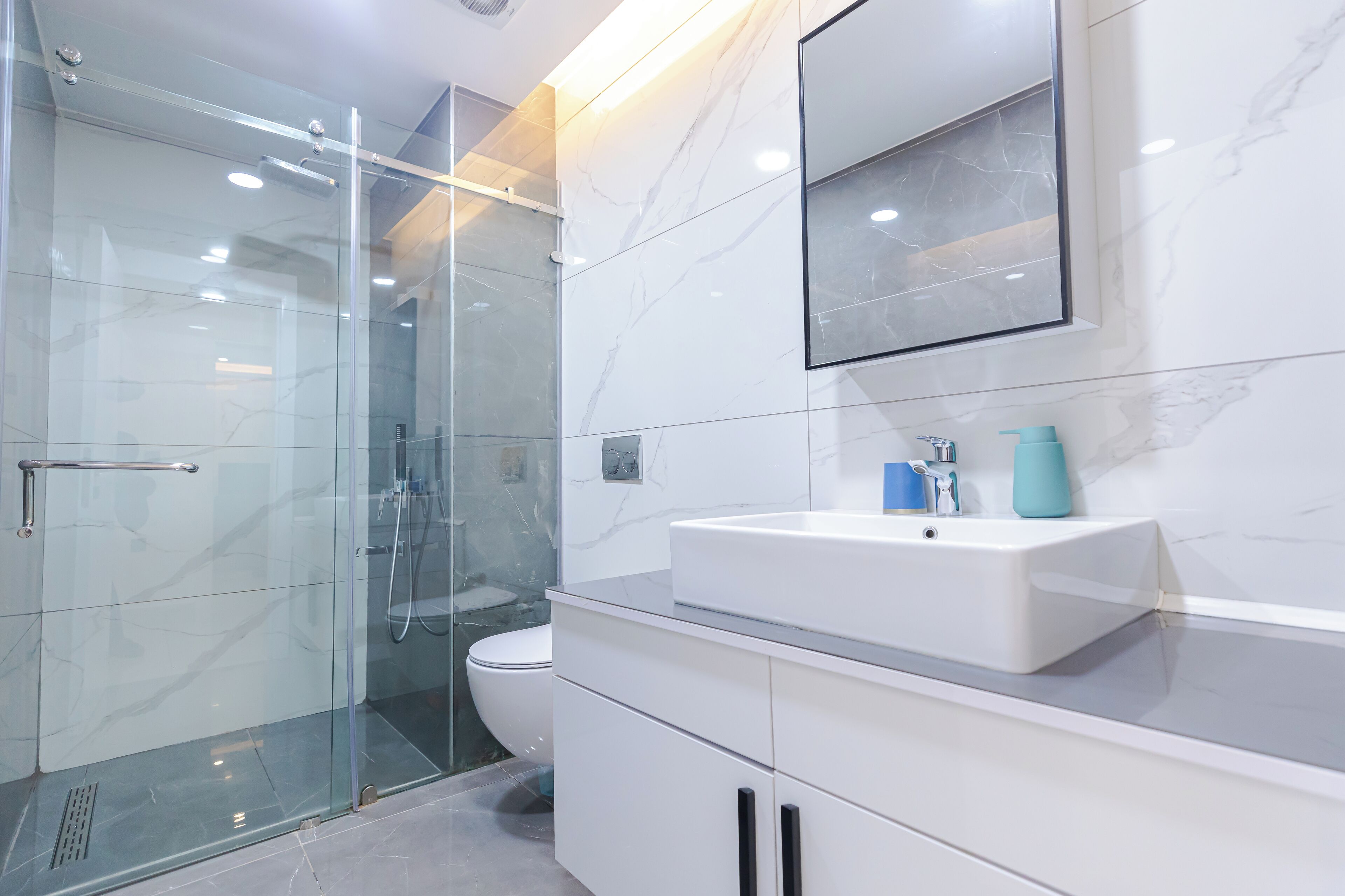 A modern bathroom with a glass shower enclosure, a white sink, and a toilet.