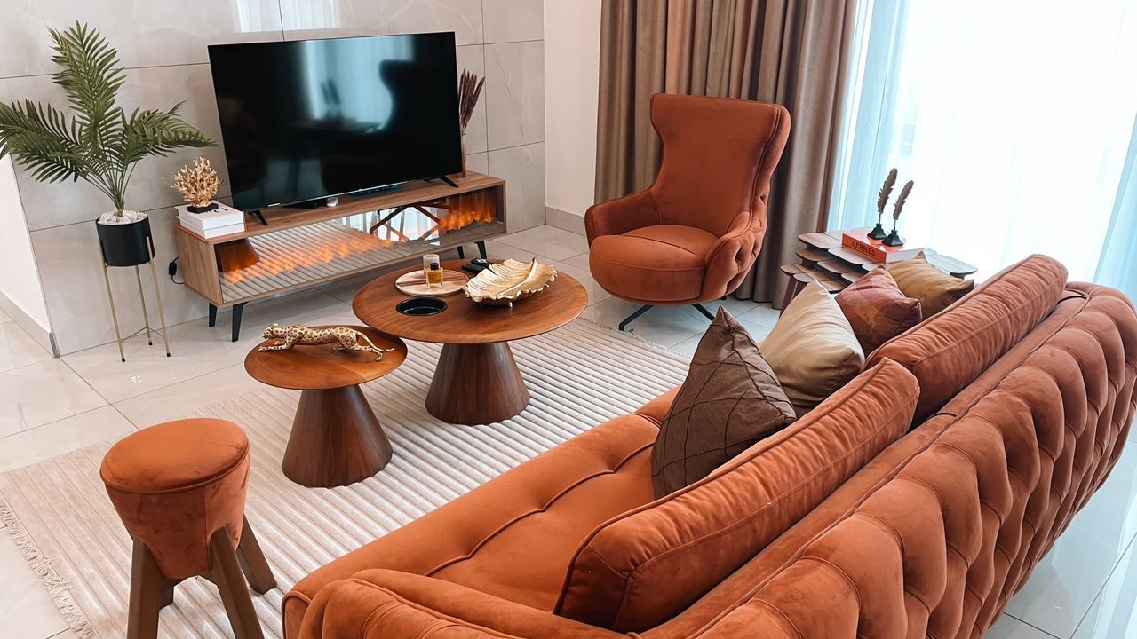 Un salon moderne avec un grand téléviseur à écran plat, un canapé, une table basse et un fauteuil.