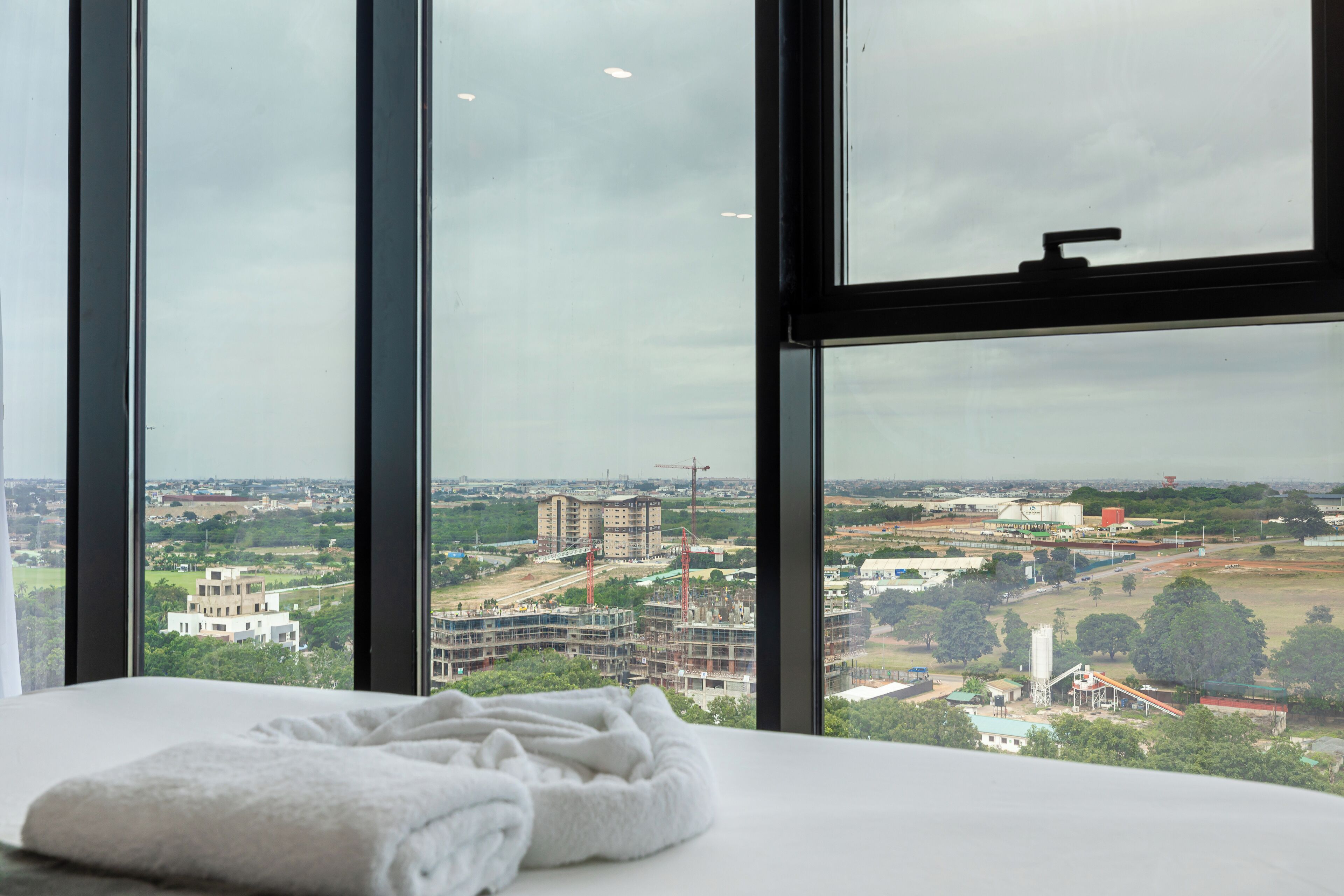 Habitación de hotel con un ventanal que ofrece vistas a una obra en construcción y edificios circundantes.