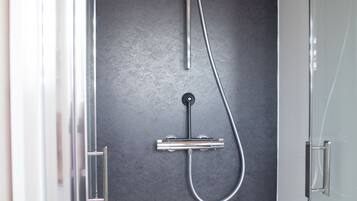 Eine moderne Dusche mit elegantem Design, einer Bedienkonsole und einem flexiblen Schlauch.