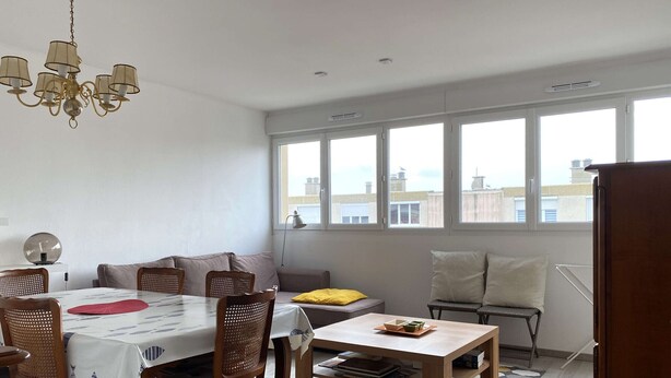 A dining area with a table, chairs, a sofa, and a window with a city view. - 3-room apartment with balcony and air conditioning in Balaruc-les-Bains (Balaruc-les-Bains)