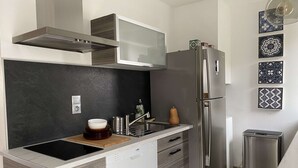 A modern kitchen with a built-in dishwasher, stainless steel appliances, and a black backsplash. - 3-room apartment with balcony and air conditioning in Balaruc-les-Bains (Balaruc-les-Bains)