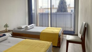 A bedroom with two beds, a chair, a lamp, and a view of a tree through the window. - 3-room apartment with balcony and air conditioning in Balaruc-les-Bains (Balaruc-les-Bains)