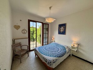 A bedroom with a bed, a chair, a window, a door, and a ceiling light. - 4-room house, 8 pers, near beach, terrace (Port-la-Nouvelle)