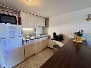 A compact kitchen with white cabinets, a gas stove, a microwave, and a coffee maker. - 4-room house, 8 pers, near beach, terrace (Port-la-Nouvelle)