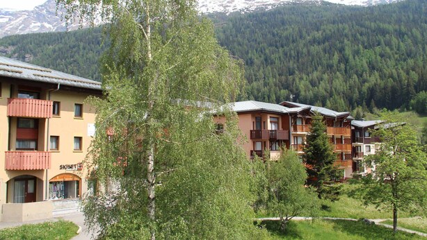 Ein Hotel mit mehreren Etagen, Balkonen und Blick auf schneebedeckte Berge.