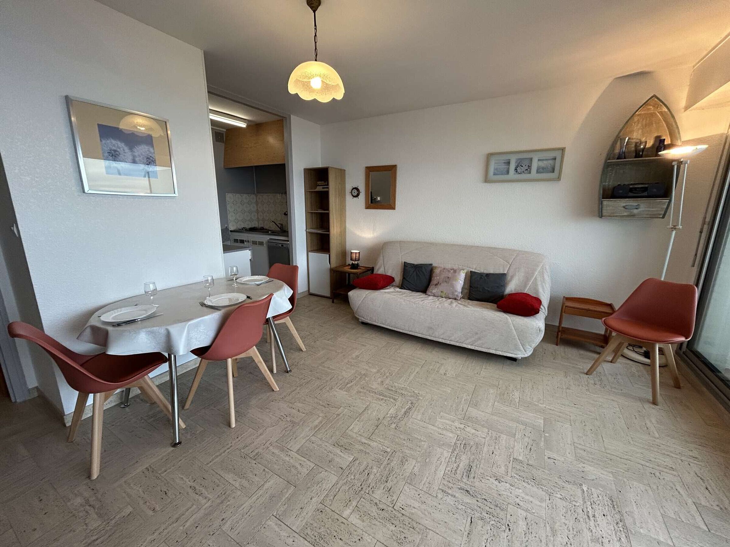 Un espace de vie compact comprenant un coin repas, un canapé et une kitchenette.