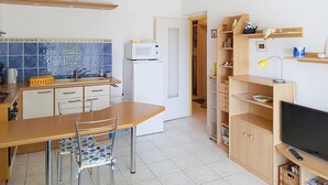 Una cocina compacta con comedor, microondas, refrigerador y televisión.