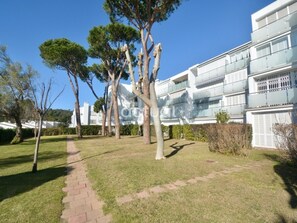 Un immeuble résidentiel avec un chemin pavé, des arbres et un ciel bleu dégagé.