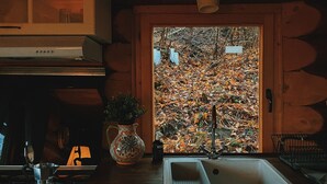 A rustic kitchen with a wooden countertop, a sink, and a stove.