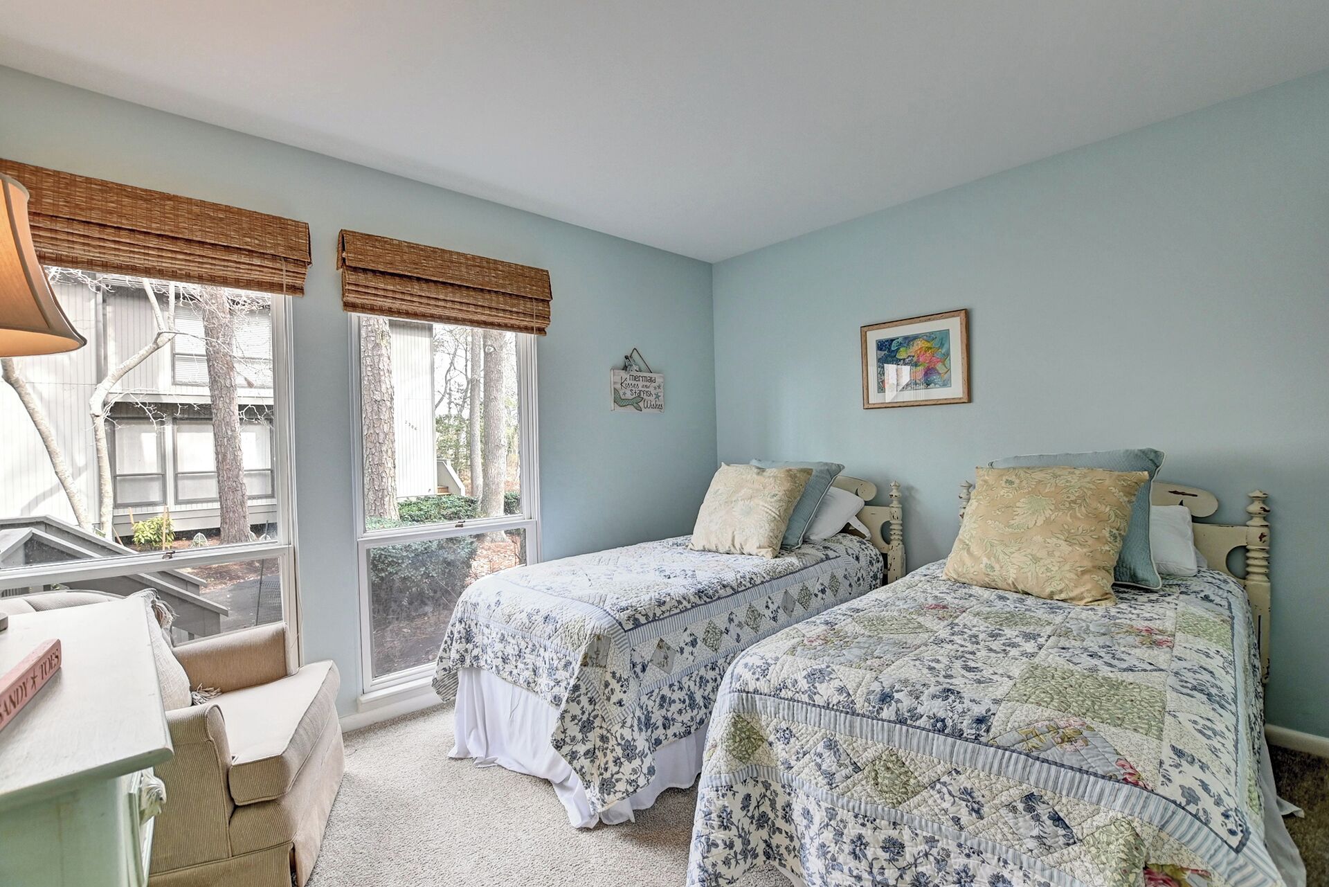 Ein Schlafzimmer mit zwei Betten, einem Schreibtisch und einem Fenster mit Jalousien.