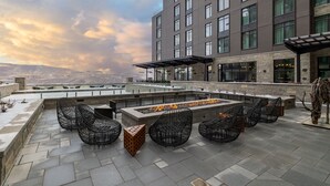 Una terraza en la azotea con una chimenea, asientos al aire libre y vistas a un paisaje montañoso.