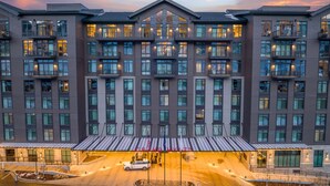 Un hotel de varios pisos con un atrio central, ventanas amplias y una zona de entrada cubierta.