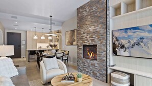Una sala de estar moderna con chimenea, comedor y cocina.