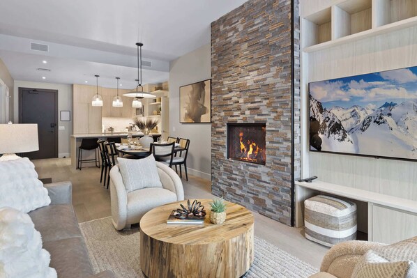 A modern living room with a fireplace, a dining area, and a kitchen. - Magnificent Deer Valley Getaway - Luxury Condo for 8 Guests | New Lifts Now Open (Park City)