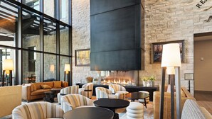 A modern lounge area with a fireplace, comfortable seating, and large windows.