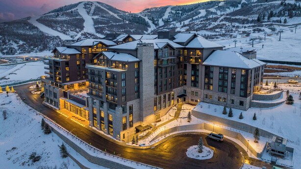A multi-story hotel with a snow-covered landscape and mountains in the background.