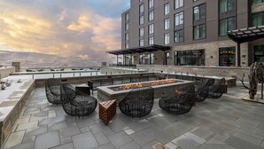 A rooftop terrace with a fire feature, seating, and a view of the mountains.