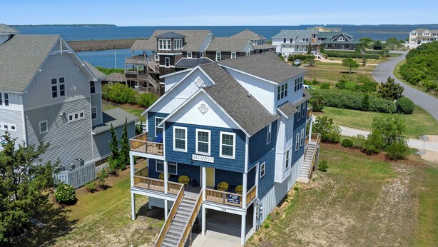A two-story house with a balcony and a staircase leading to the entrance. - Bela Vista: Stunning Water Views, Hot Tub, Pets OK (Nags Head)