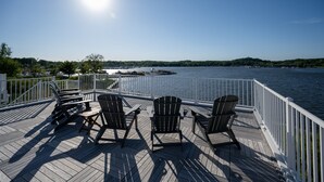 Een terras met Adirondack-stoelen met uitzicht op een wateroppervlak.