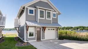 Een tweelaags huis met een garage, een voordeur en uitzicht op een meer.