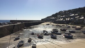 A coastal area with boats docked along the shore and a stone wall on the left. - Stylish Dog-Friendly Cottage with Stunning Sea Views in Mousehole, secure garden (Mousehole)
