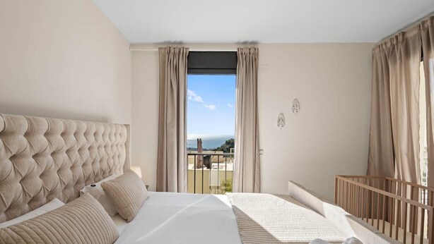 Una habitación de hotel con una cama grande, un balcón con vistas y una barandilla de madera.