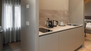 A modern kitchen with a built-in sink, a coffee maker, and a wine bottle. - Agriturismo Pra' dell'Ort (Valdobbiadene)