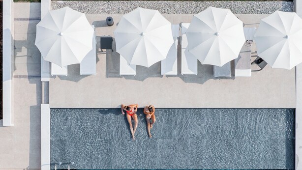 An aerial view of a swimming pool with two people relaxing under white umbrellas, surrounded by lounge chairs and a well-maintained lawn. - Agriturismo Pra' dell'Ort (Valdobbiadene)