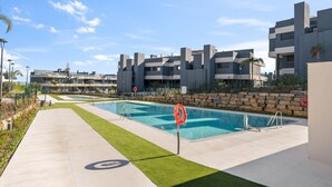 A modern pool area with a clear sky, a concrete pathway, and a stone wall. - RDR467 - Luxury penthouse with sea view rooftop (Estepona)