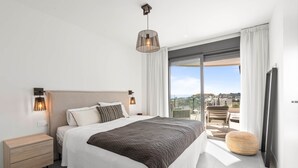 A modern bedroom with a large bed, bedside lamps, a nightstand, a round ottoman, and a balcony with a view. - RDR467 - Luxury penthouse with sea view rooftop (Estepona)