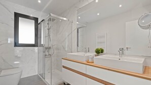 Un bagno moderno con box doccia in vetro, due lavandini e uno specchio grande.