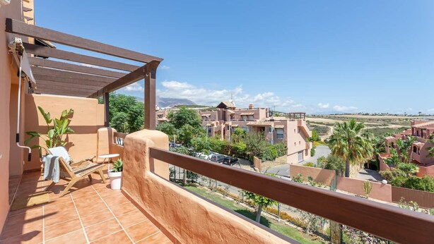 Un balcon donnant sur un quartier résidentiel, avec des maisons et de la verdure.