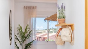 Un baño con un ventanal grande, una planta en maceta, un perchero y una estantería con una planta.