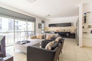 A modern apartment with a living area, kitchen, and large windows. - MAMAD Stunning 2BR/2BA SeaView Apt| By SweetyGuest (Tel Aviv-Yafo)